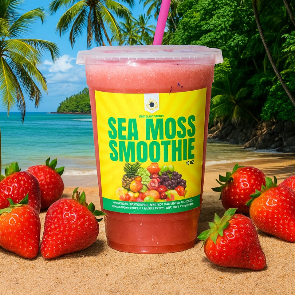 A strawberry sea moss smoothie with a pink straw sits on a sandy beach surrounded by fresh strawberries.